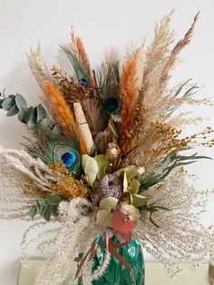 a vase filled with lots of different types of flowers and feathers on top of a table