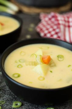 two black bowls filled with soup on top of a table