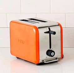 an orange and silver toaster sitting on top of a white tiled counter next to a wall