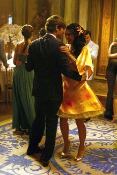 a man and woman dance together in an ornate room with other people around the room