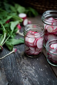 several jars filled with sliced radishes on top of a wooden table