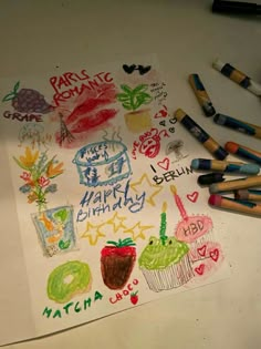 some crayons are laying on top of a sheet of paper with writing and drawings