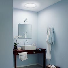 a white sink sitting under a bathroom mirror next to a wooden table with towels on it