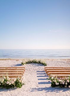 a row of wooden benches sitting on top of a sandy beach next to the ocean