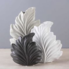 two white and black vases sitting on top of a table