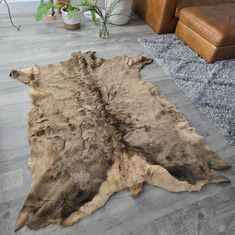 a brown and black animal skin rug on the floor in a living room next to a couch