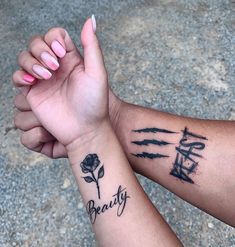 two hands holding each other with tattoos on their arms and the words beauty written in cursive writing