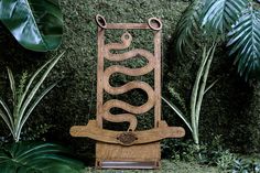 a wooden chair sitting on top of a lush green field next to trees and plants