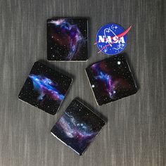 four square coasters with the nasa logo on one side and galaxy in the background