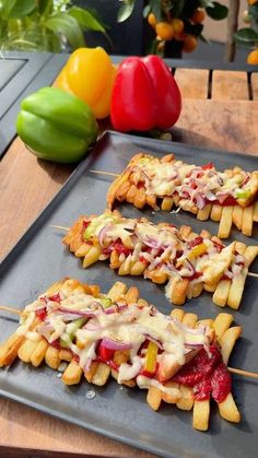 several skewered food items are sitting on a tray next to peppers and tomatoes