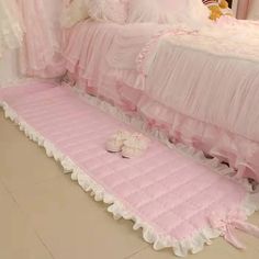 a pink bed with white ruffled bedspread and teddy bear sitting on it