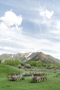 an outdoor wedding set up in the middle of a field with mountains in the background