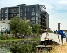 an old boat is sitting in the water next to some tall buildings and other buildings