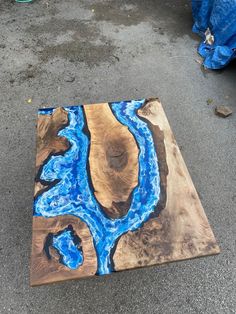 a piece of wood that has been painted with blue and black paint on it, sitting on the ground