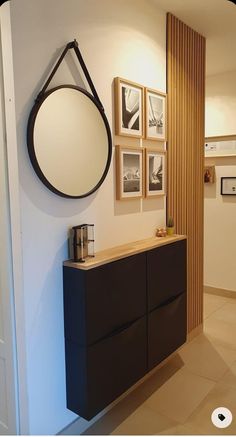 a bathroom with a black cabinet and pictures on the wall above it, along with a round mirror