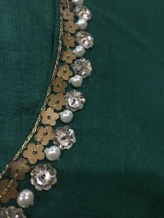 a close up of a necklace with flowers and pearls hanging from it's sides