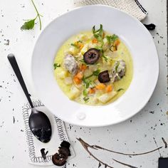 a white bowl filled with food on top of a table next to utensils