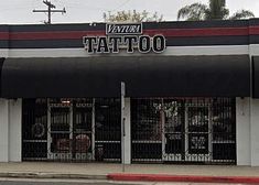 the front of a tattoo shop with black and red stripes on it's awnings