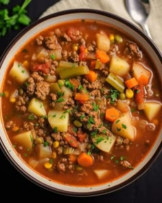 a bowl of soup with meat, potatoes and carrots