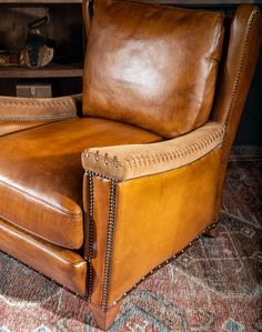 a brown leather chair sitting on top of a rug