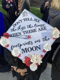 Grad cap that reads "Don't tell me the sky's the limit when there are footprints on the moon." It's white with flowers and rhinestones around the edges. White Grad Cap Decoration, Artsy Grad Cap Ideas, Police Graduation Cap Ideas, Graduation Cap Designs Meaningful, Space Themed Graduation Cap, Grad Cap Inspo Sza, Almost There Graduation Cap, Cute Graduation Caps High Schools