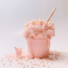 an ice cream sundae with sprinkles and candy on the rim, in a pink cup