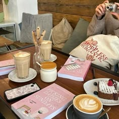 a woman taking a selfie at a table with coffee, cakes and other items