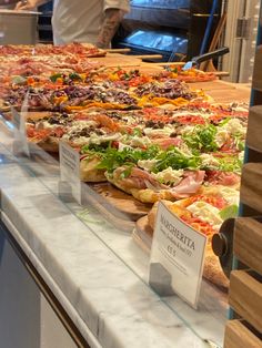 many different types of pizzas on display in a case at a restaurant or bar