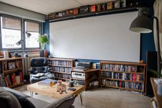 a living room filled with furniture and a large white board on the wall behind it