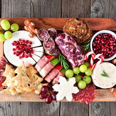 a wooden platter filled with meats, cheeses and crackers on top of a table