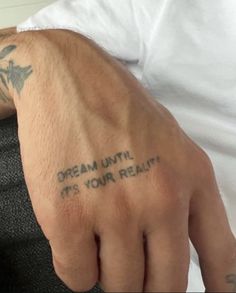 a man with a tattoo on his left hand and the words dream until it's your reality