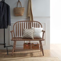 a wooden bench sitting next to a coat rack and basket on top of a hard wood floor