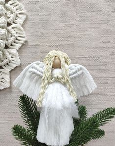 an angel ornament hanging on a wall next to a pine cone with leaves