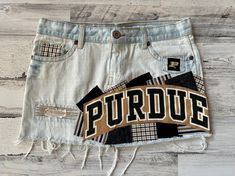 *READY TO SHIP* This ladies size 8 Purdue University Boilermakers themed denim patch skirt the perfect way to show support to your favorite school! I began with a size 8 gently worn Old Navy brand denim skirt and have sewn Purdue University fabrics on the front & back of the skirt along with a rescued t-shirt piece to create a unique one of a kind design.   The following details & measurements will help you decide if the fit would be right for you. *Fabric content: 100% cotton *Waist laying flat: 16.75" *Around the "outside" of the waistband, through the belt loops: 34" *Hip laying flat: 19.25" *Length (measured from the side): 13" The edges of the fabric pieces will intentionally fray. This gives them the desireable "vintage" fray appearance. The more the skirt is washed & worn, the bette Patch Skirt, Bed Party, Rush Week, Boilermaker, Patch Denim, Purdue University, Denim Patches, Halloween Shopping, Denim Skirt