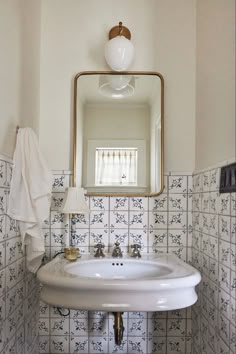 a white sink sitting under a bathroom mirror next to a wall mounted faucet