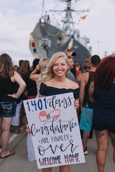 a woman holding a sign in front of a boat