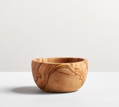 a small wooden bowl sitting on top of a table next to a white wall and floor