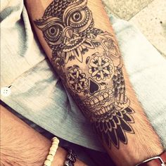 an owl and skull tattoo on the arm