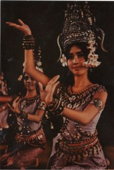 two women dressed in ethnic garb and headdress, one holding her hands up