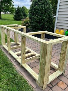 a wooden planter box sitting on top of a brick walkway in front of a house