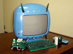 a blue computer sitting on top of a wooden desk next to a keyboard and mouse