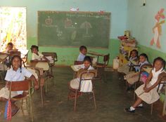 several children sitting at desks in front of a chalkboard