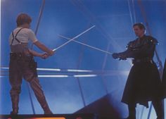 two men in star wars costumes holding lightsabes with one man pointing at the other