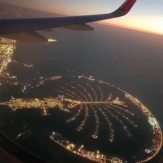 an aerial view of the city lights and water from inside an airplane window at night