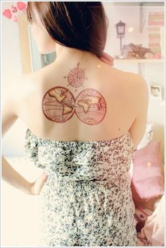 a woman with a tattoo on her back that has two globes in the middle