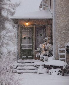 a snow covered house with steps leading up to the front door and lights in the window