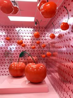 some red apples hanging from the ceiling in a room with pink walls and polka dots