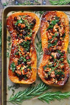 two delicacy stuffed sweet potatoes on a baking sheet with fresh herbs and nuts