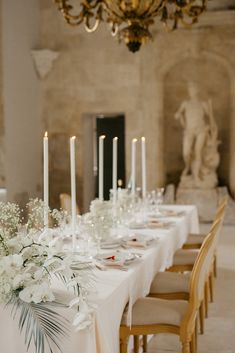 a long table is set with white flowers and candles for an elegant dinner or reception