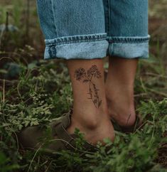 a woman's foot with a flower tattoo on her left ankle, in the grass